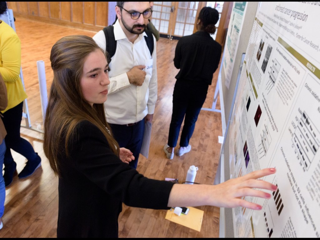 Rachel Stucky points to her poster when presenting.